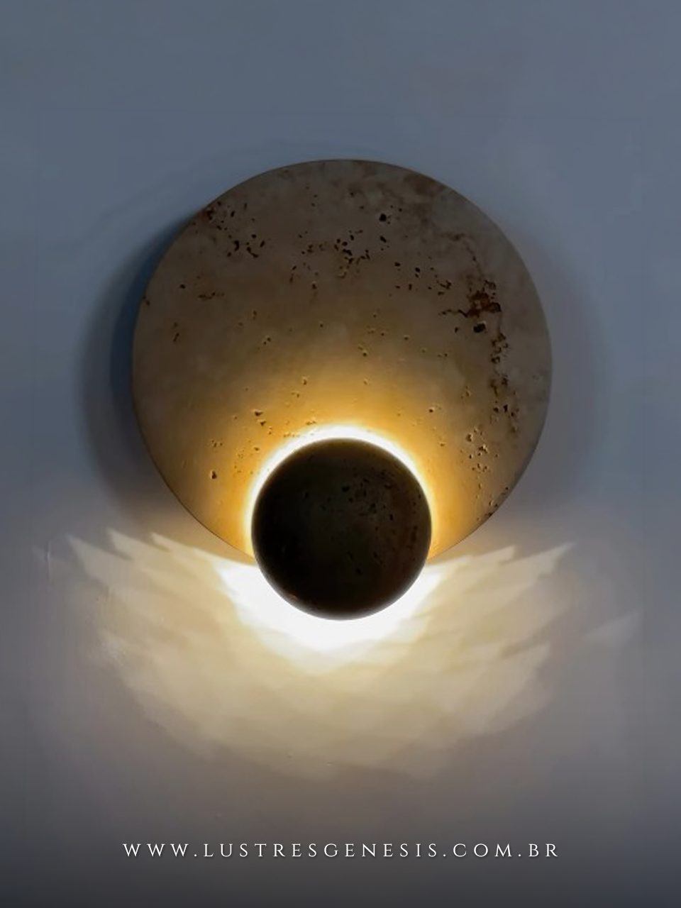 Arandela decorativa de pedra natural travertino Bellagio de 23cm de di&acirc;metro instalada em parede, iluminando suavemente, ideal para cabeceira de cama, lavabos e hall.